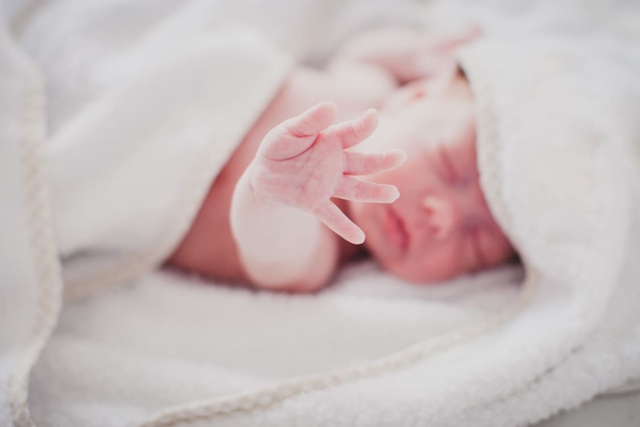 Neugeborenes streckt Hand in die Kamera
