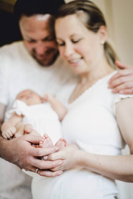 Eltern halten die Füße ihres Babys zusammen in ihren Händen
