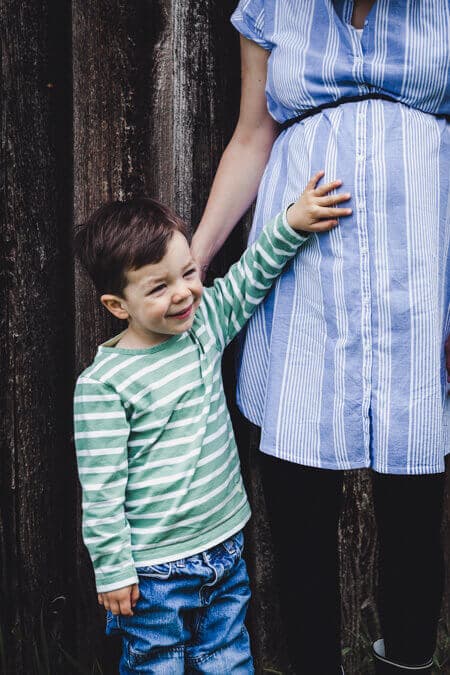Nahaufnahme von Junge der die Hand auf den Babybauch der Mutter hält