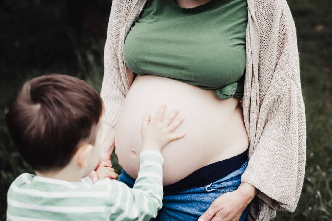 Nahaufnahme von Junge der die Hand auf den nackten Babybauch der Mutter hält