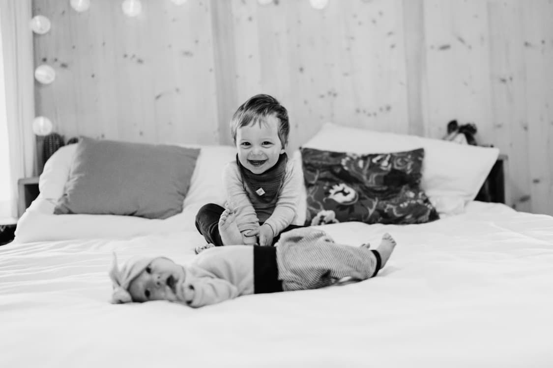 Baby und Bruder auf einem Bett