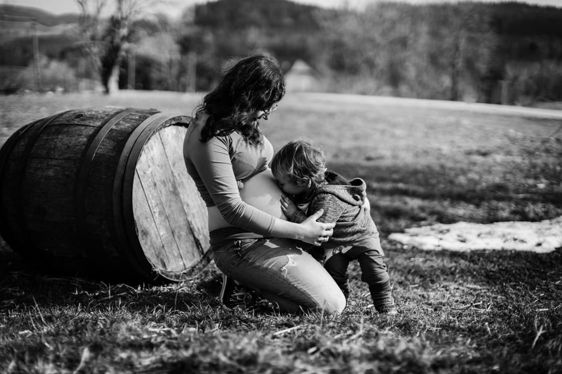 Kind küsst Babybauch von der Mama