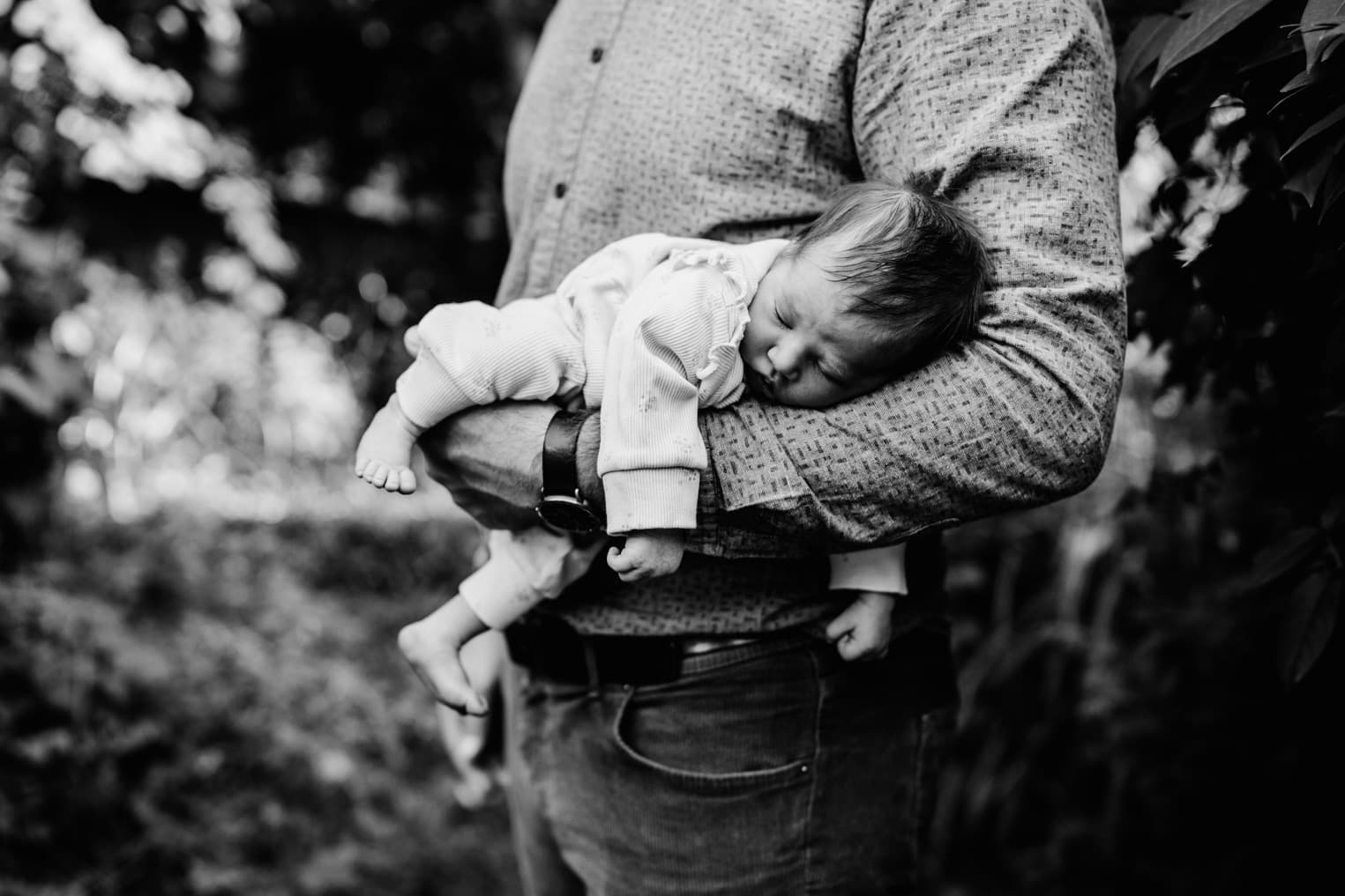 Baby schläft auf dem Arm des Vaters
