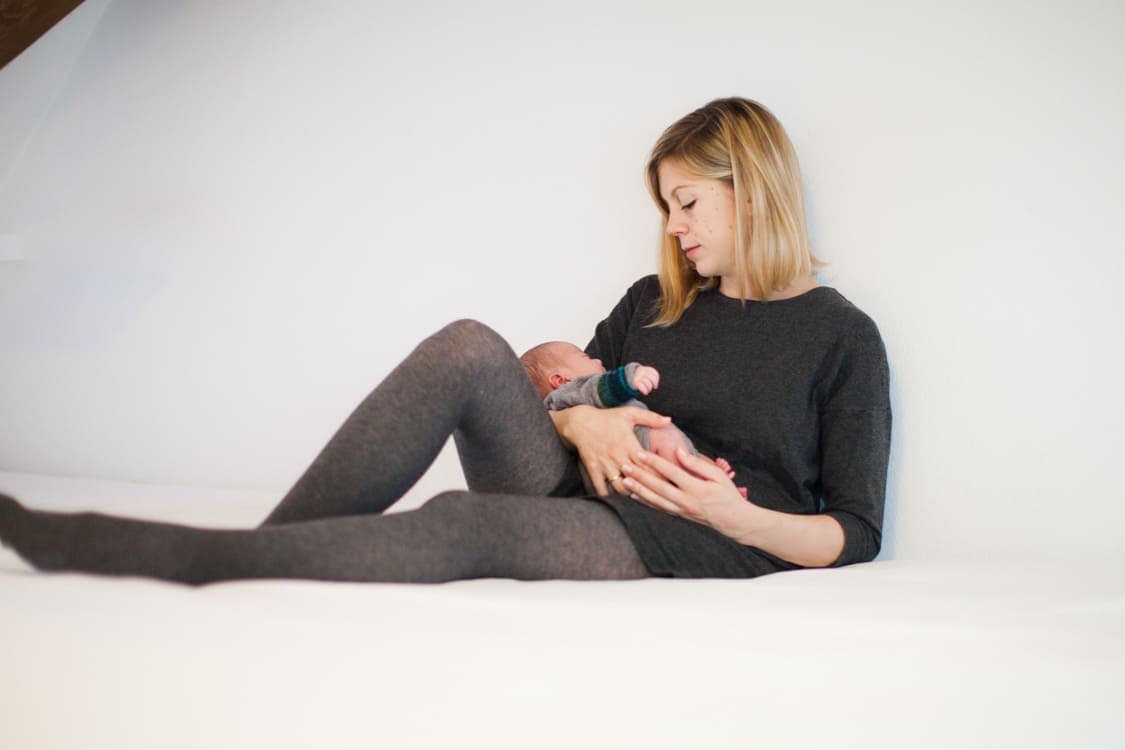 Mutter sitzt auf dem Bett und hält ihr Baby im Arm
