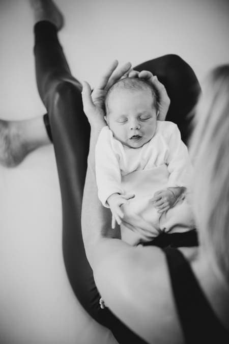 Blick von oben auf ein Neugeborenes auf dem Schoß der Mutter