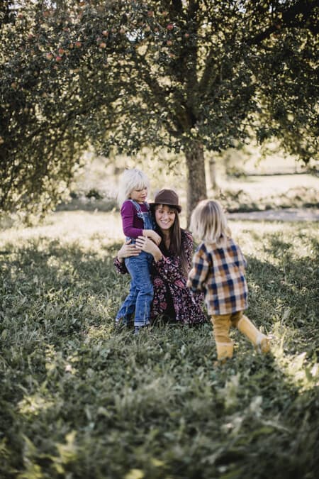 Mutter mit ihren beiden Kindern unter einem Apfelbaum