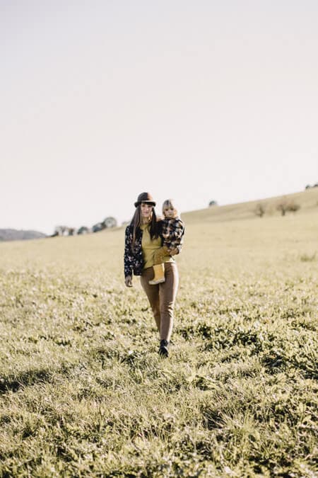 Frau läuft über ein Feld mit Kind auf dem Arm