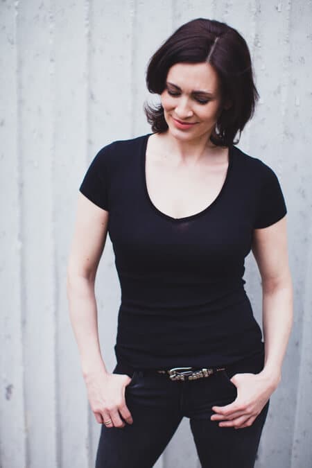 Frau mit schwarzer Hose und schwarzem T-Shirt schaut nach unten