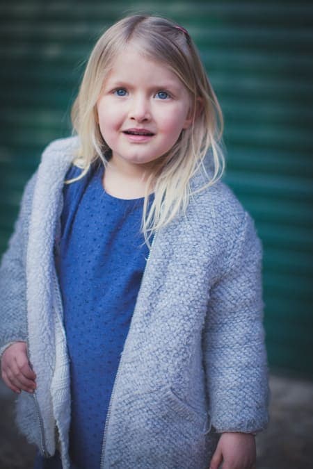 Mädchen mit blauem Kleid steht vor Rolltor