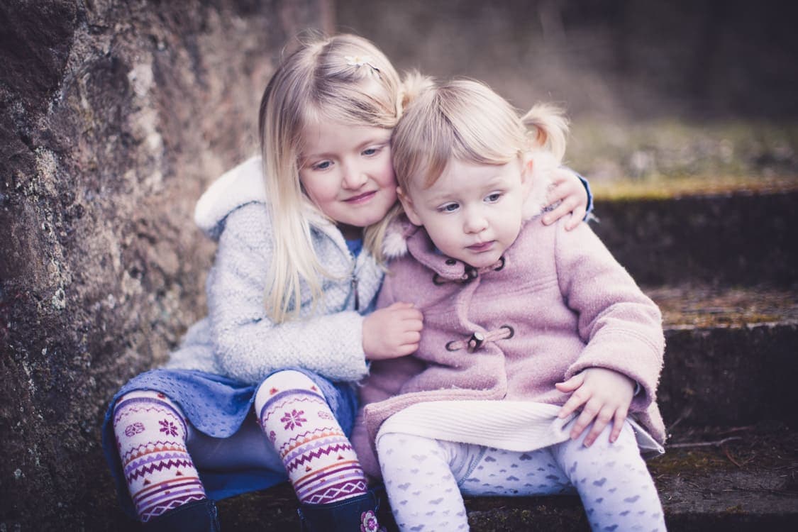 Schwestern sitzen auf einer Treppe und umarmen sich