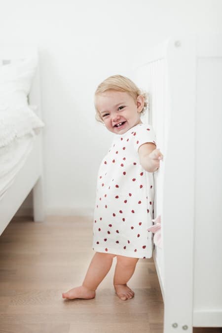 Kleines Mädchen steht am Gitterbett