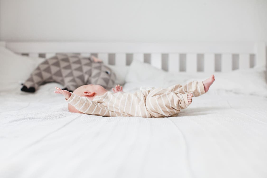 Neugeborenes liegt auf einem Bett und schaut weg von der Kamera