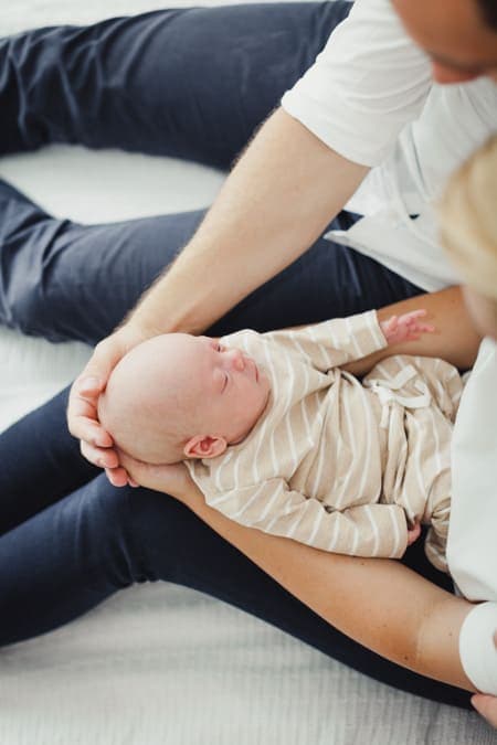 Eltern umfassen Köpfchen von ihrem Neugeborenen