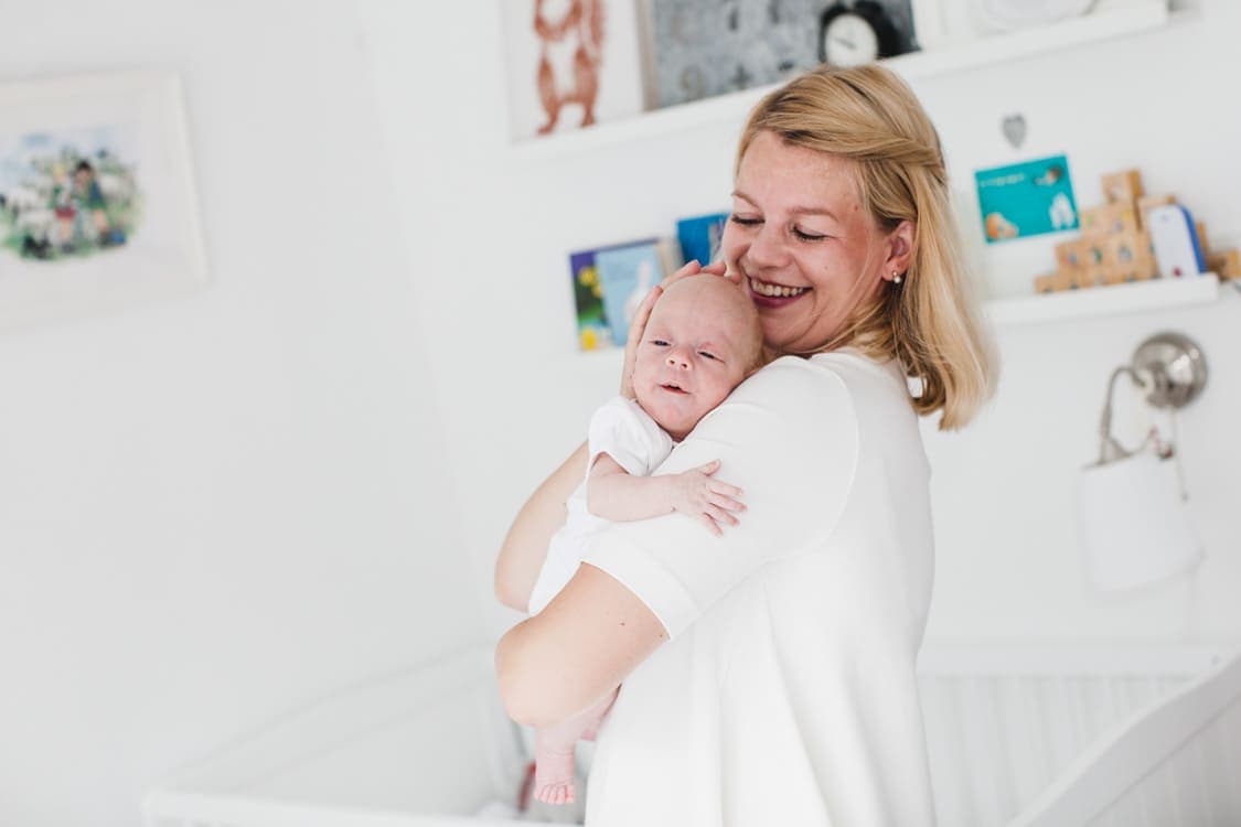 Mutter steht im Kinderzimmer mit Baby auf dem Arm