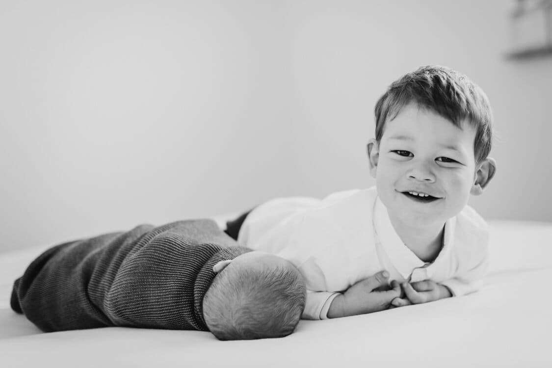 Junge liegt mit Baby auf dem Bett