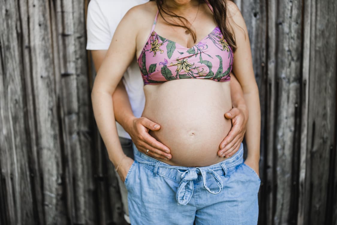 Babybauch vor Scheunentor