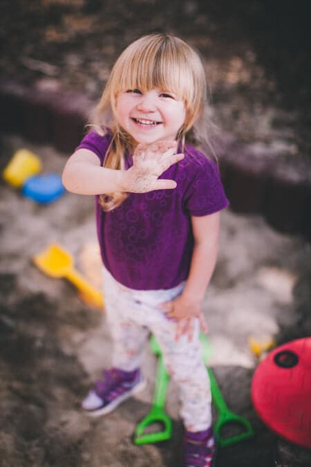 Mädchen steht im Sandkasten