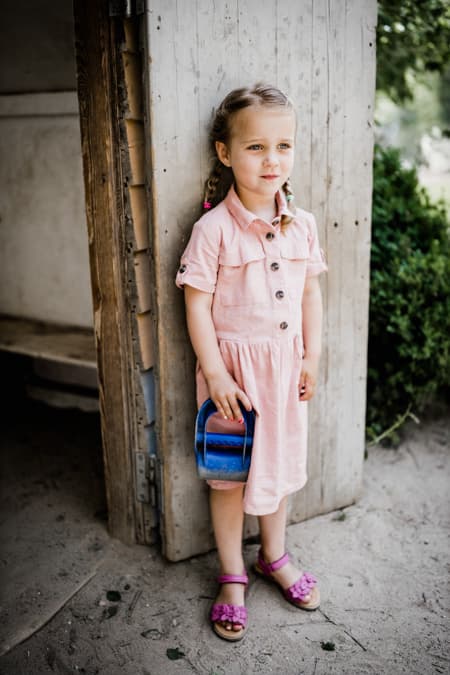 Maedchen steht an einem Spielhaeuschen