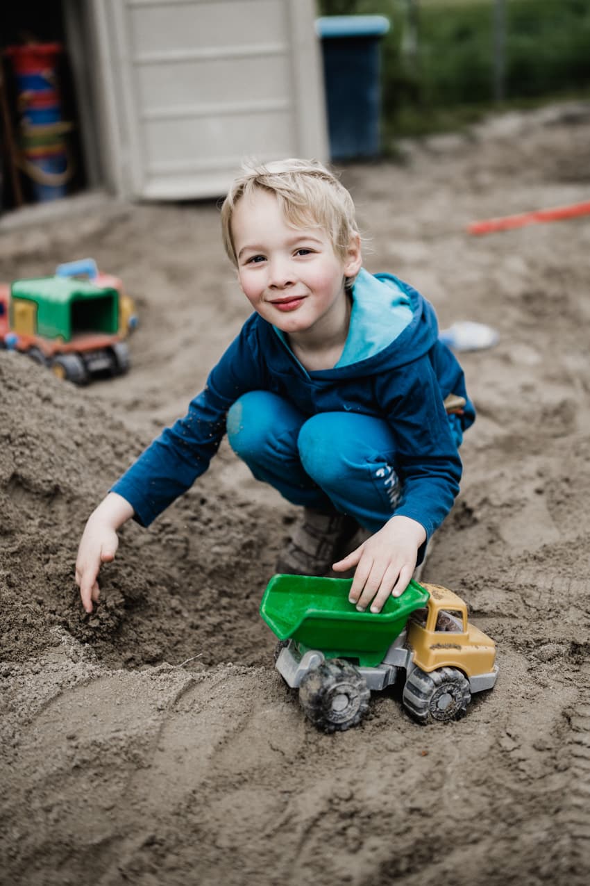 Junge im Sandkasten mit Laster