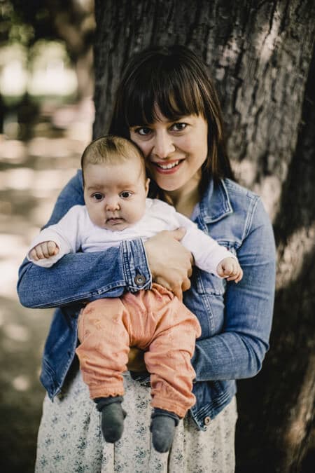 Portrait von Frau mit Baby auf dem Arm vor einem Baum