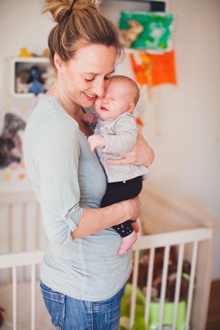 Mama mit Baby Tochter auf dem Arm im Kinderzimmer