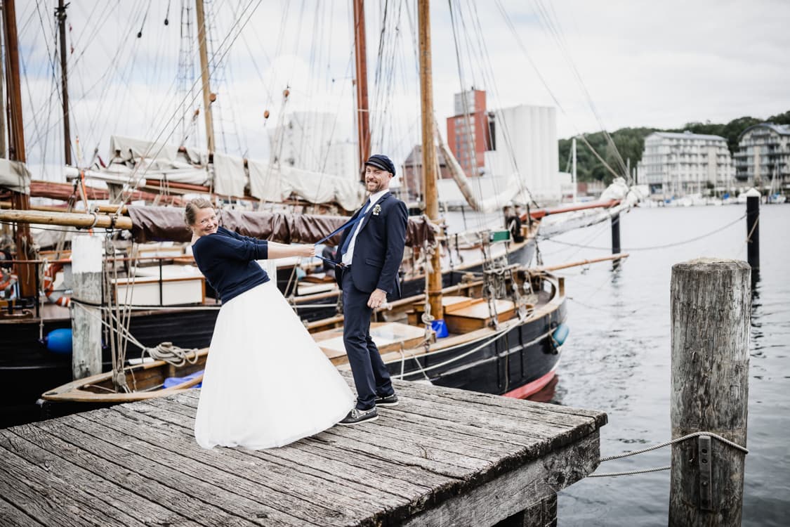 Braut zieht Braeutigam an seinen Hosentraegern