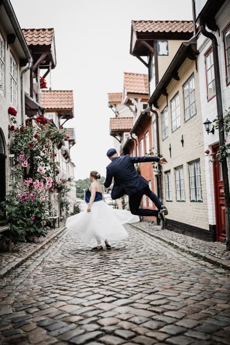 Brautpaar tanzt und springt in einer Gasse