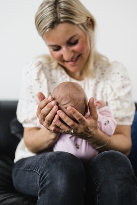 Babykopf in den Händen der Mutter