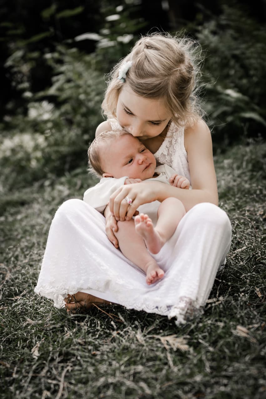 Mädchen mit Babyschwester auf dem Schoß