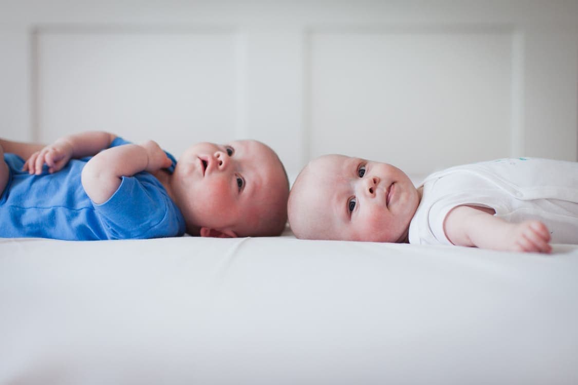 Zwillinge liegen Kopf an Kopf auf einem Bett