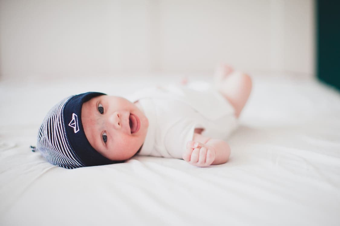 Baby liegt auf dem Rücken auf einem Bett und lacht