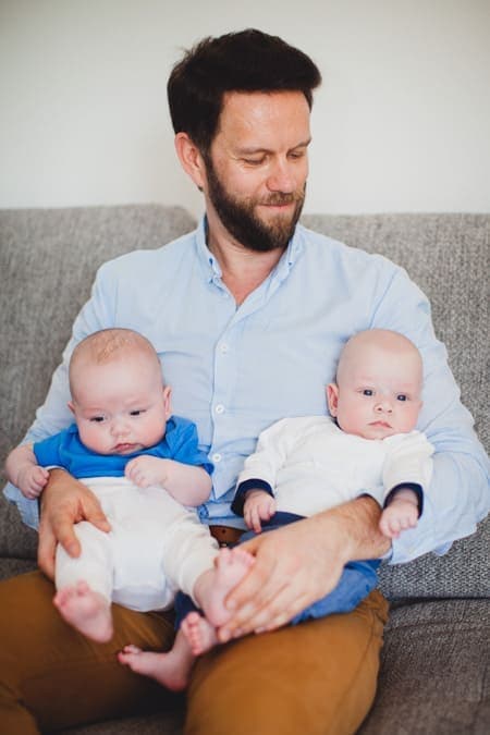 Zwillingsbabys sitzen auf dem Schoß vom Papa