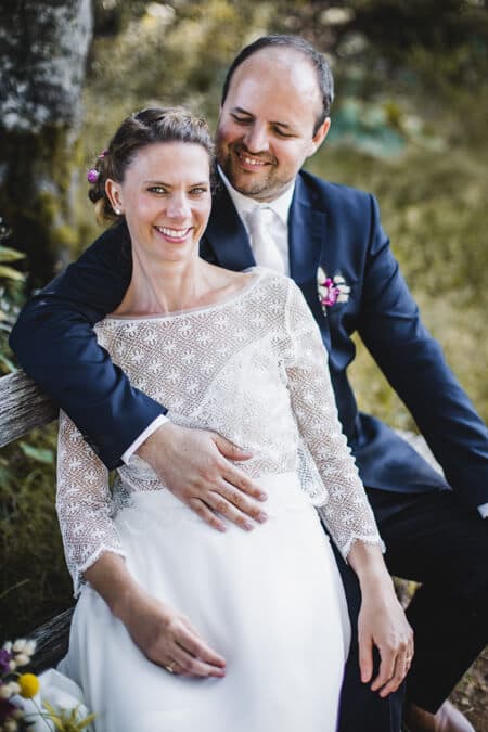 Braut und Bräutigam sitzen auf einer Bank im Wald