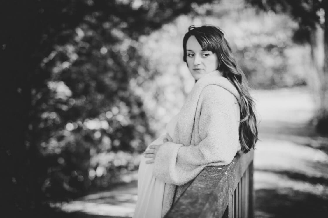 Frau mit Babybauch auf einer Brücke in Schwarz Weiß