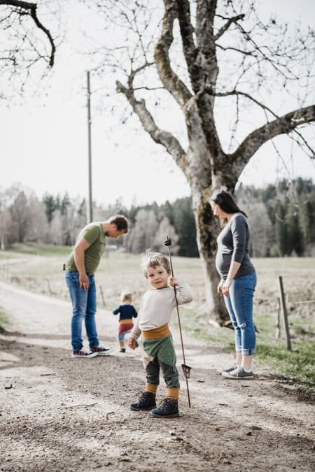 Junge mit Stab in der Hand und Familie im Hintergrund