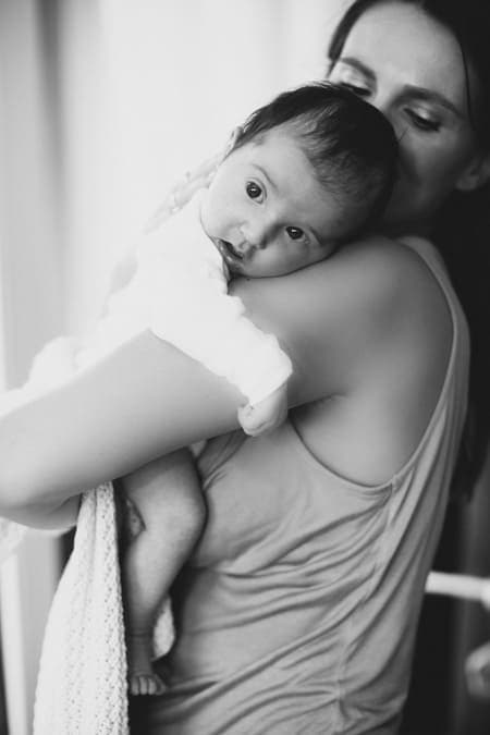 Baby hängt auf der Schulter von Mama