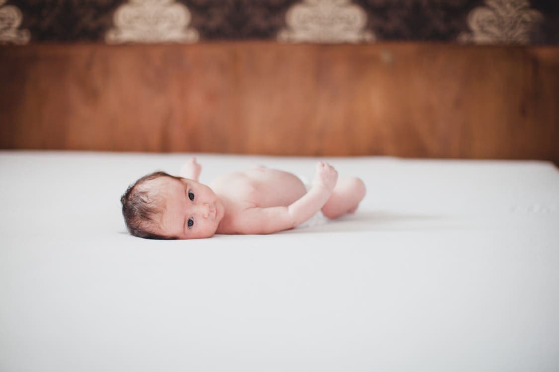 Baby in Winder liegt auf Bett