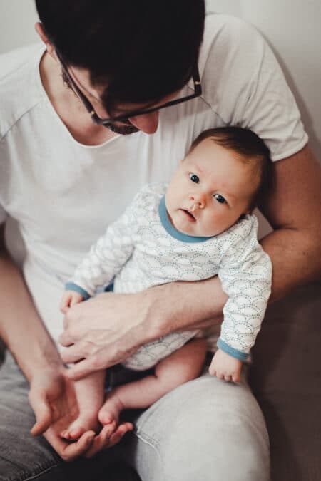 Vater hält seinen kleinen Sohn auf dem Schoß. Blick von oben auf das Baby.
