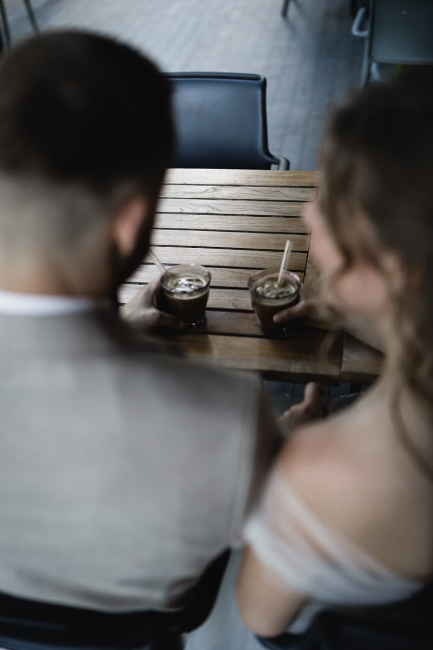 Blick über Schultern des Brautpaars, beide halten Kaffee entspannte Hochzeitsfotografie