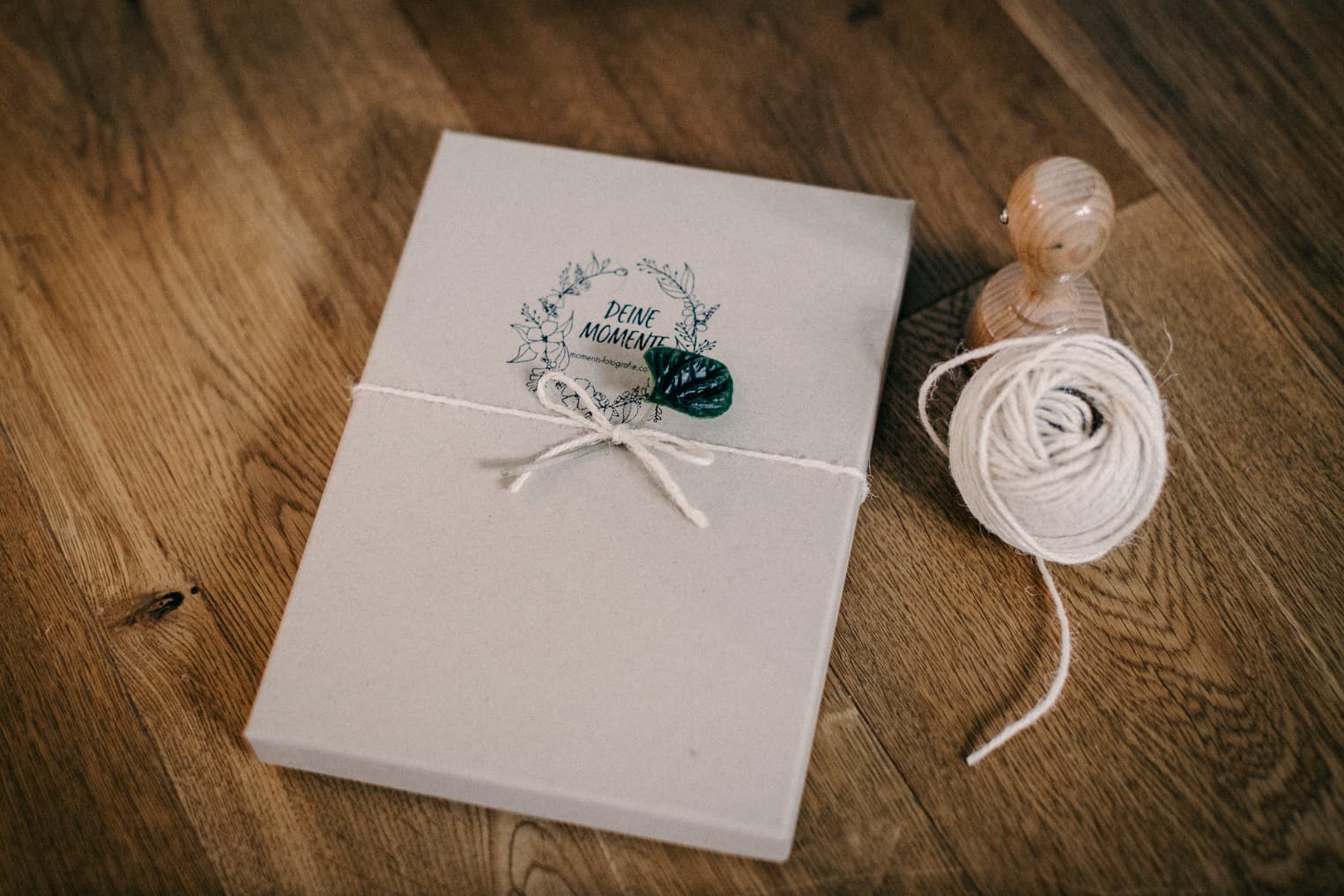 Verpackte Fotobox mit Stempel und Schnur daneben liegend hochwertige Fotoabzüge aus dem Fotoshooting