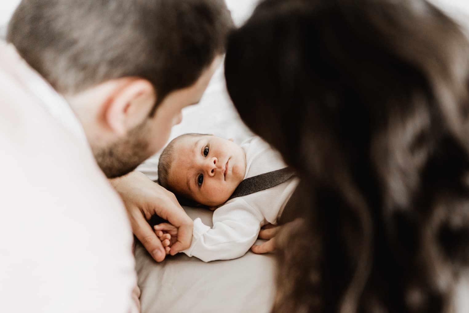 Mama und Papa schauen liebevoll auf ihr Baby während des Shootings zu Hause