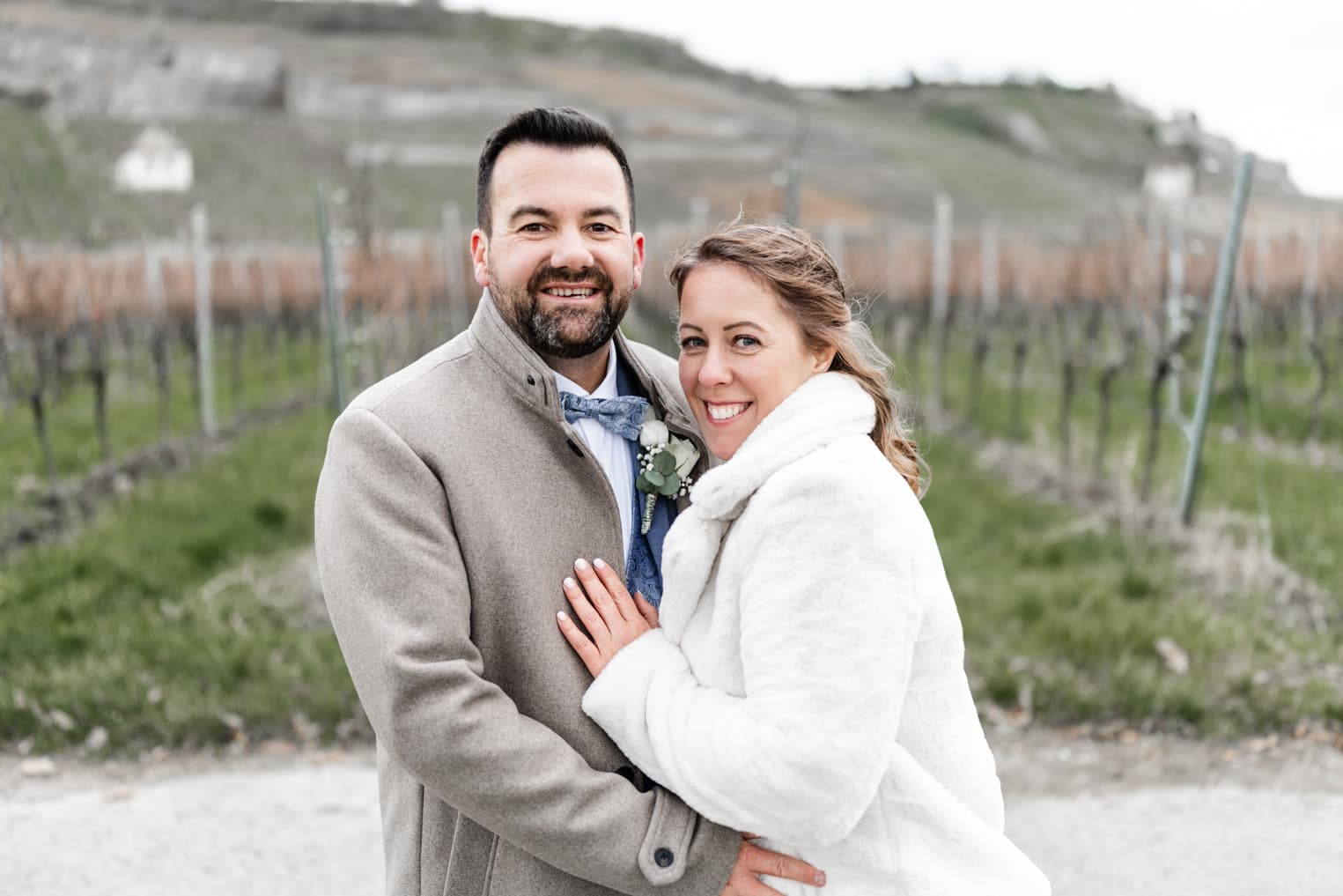 Brautpaar steht vor Weinreben, natürliche Hochzeitsfotografie