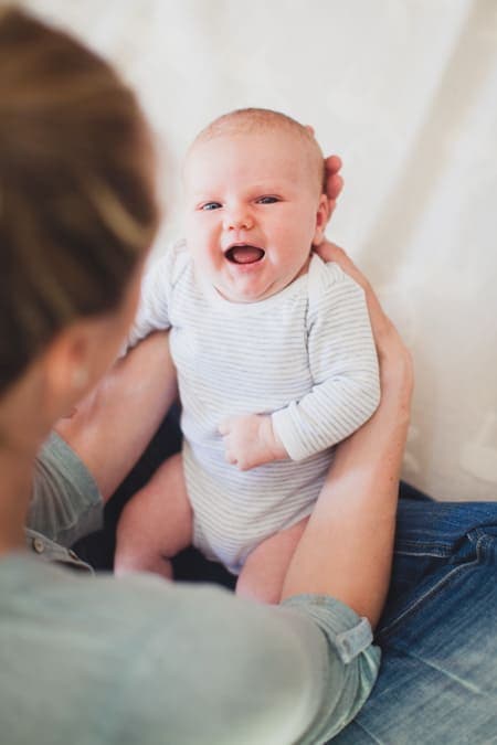 Blick von oben. Baby lacht Mutter an.