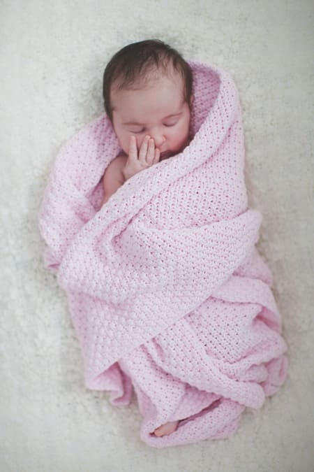 Baby in rosa Decke eingewickelt