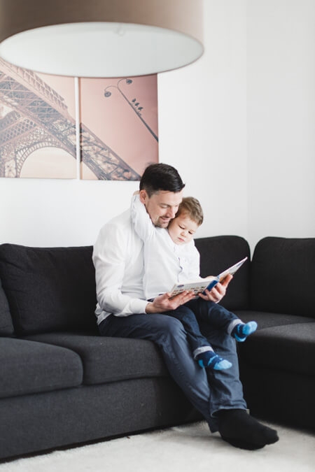 Vater und Sohn lesen ein Buch auf dem Sofa