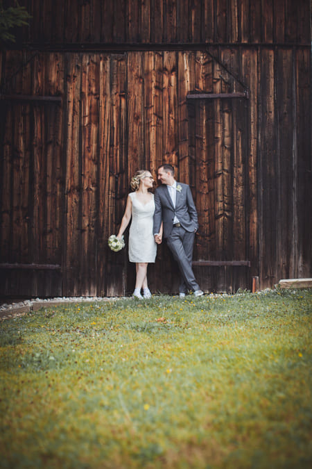 Brautpaar leht an Scheunentor und schaut sich an