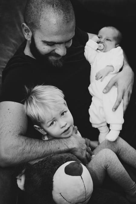 Schwarz-weiß Fotografie. Vater mit seinen beiden Kindern und Teddybär.