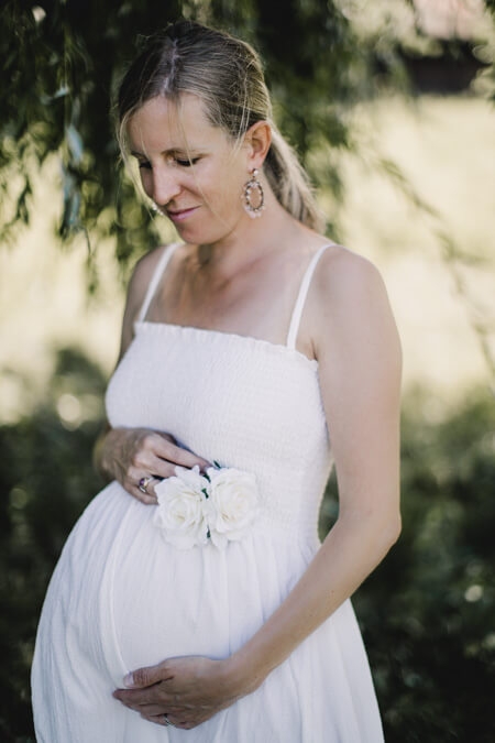 Frau im weißen Kleid und Babybauch