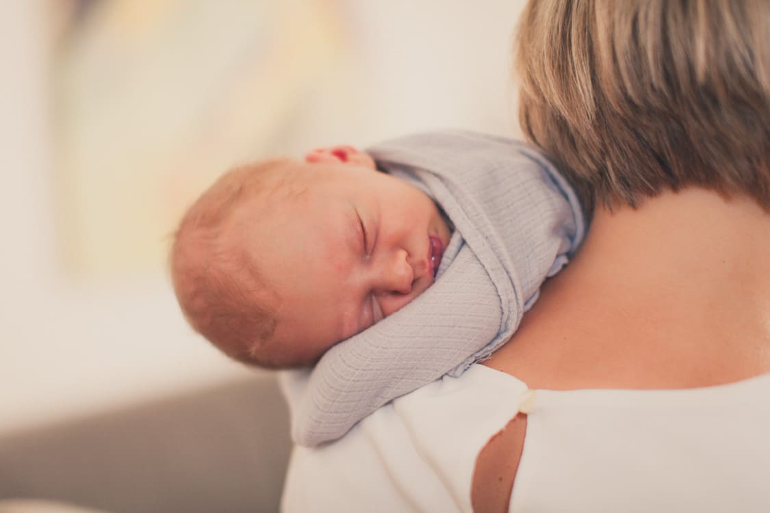 Babyschläft eingepuckt auf der Schulter der Mutter