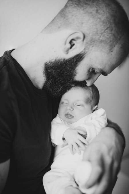 Schwarz-weiß Fotografie. Vater gibt seinem Baby einen Kuss auf den Kopf.